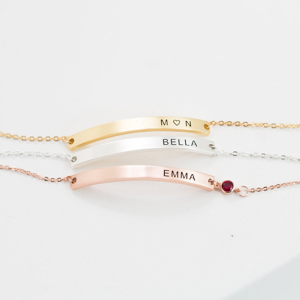 Three Thin Name Bar Bracelets in gold, silver, and rose gold—engraved M♡N, BELLA, and EMMA (with a red gem)—make stunning personalized jewelry for any dainty bracelet collection.