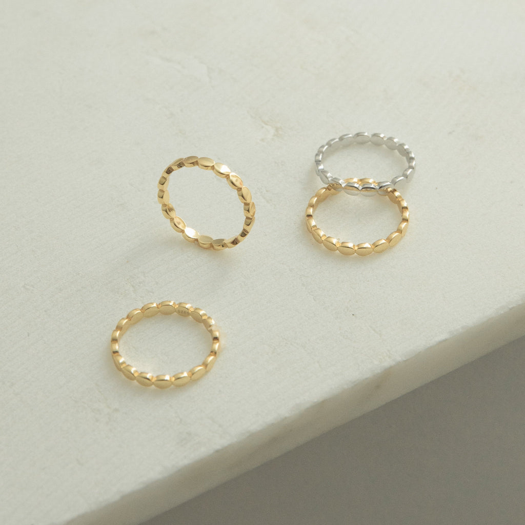The Beaded Ring, with its textured design in gold and silver tones, is displayed on a light surface—ideal for stacking or wearing solo as a unique piece in your jewelry collection.