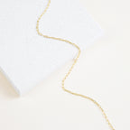 The Dainty Link Chain Necklace in Rose Gold features delicate rectangular links draped over a white, speckled surface—perfect for layering with your favorite necklaces.