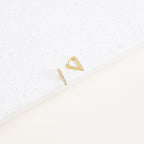 The Ezra Triangle Earrings—featuring one geometric triangle and one slim bar—are displayed on a white textured surface, highlighting their modern design and subtle pavé texture.