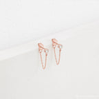 Birthstone Chain Studs in rose gold feature clear gemstones and a delicate chain, shown on a white textured background—versatile earrings ideal for any occasion.