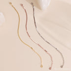 Three minimalist chain bracelets in gold, rose gold, and silver are displayed on a light beige background, perfectly complementing any polished ankle jewelry or pairing seamlessly with the Herringbone Anklet.