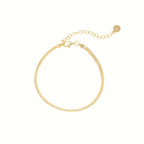 The Herringbone Anklet features a delicate gold chain with an adjustable clasp and small round charm, perfect for a minimalist jewelry style or polished ankle look. Displayed on a white background.