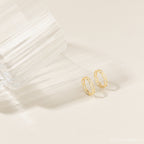 Pair of the gold link rings placed closely together on a fabric backdrop, highlighting the linked design and muted gold tone.