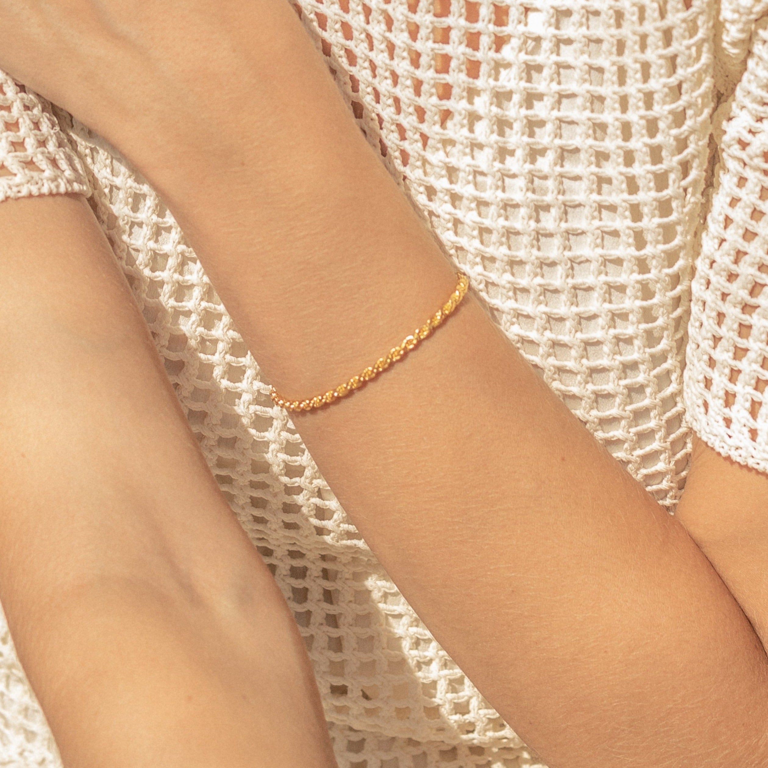 A person wearing the Rope Chain Bracelet styled with a white textured, netted top.