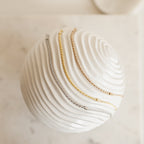 Three Rope Chain Bracelets—one silver, one gold, and one rose gold with a subtle twisted design—are draped over a white textured sphere.