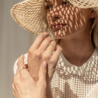 A woman wearing a sunhat and the Pave Dome Ring, sunlight casting patterned shadows across her face and hands.