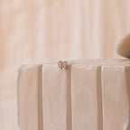 A pair of Baguette Diamond Studs, small and subtle, rest elegantly on the edge of a textured white surface.