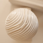 Gold and Silver Pearl Bead Necklaces displayed on a white sculptural object with curved, ridged texture.