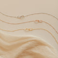 The Linked Pendant Necklace in Silver is elegantly displayed on a cream fabric background.