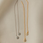 Two pairs of Lux Threader Earrings, one silver and one gold, each featuring a delicate star charm, rest on beige fabric. These chic earrings add a subtle celestial accent to any outfit.