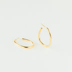 A pair of Anine Oval Hoops is displayed in gold against a plain white background.