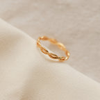 The Braided Ring shines elegantly on a white cloth, ideal for stacking or pairing with your favorite silver band.