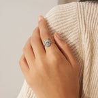 A hand wearing a silver Pet Portrait Ring rests on a beige ribbed sweater, highlighting elegant jewelry featuring a custom cat-shaped design.