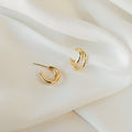 Zoey Duo Hoops rest on soft, white fabric with gentle folds—ideal for stacking or pairing with our Double Huggie Hoops for a chic, layered ear look.