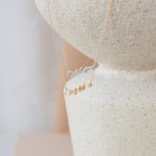 The Mrs. Necklace, available in gold and 925 sterling silver, is showcased on a textured stone surface—an ideal choice for a thoughtful wedding gift.