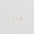 The Saylor Huggies are two small gold hoop nose rings adorned with tiny clear gemstones, displayed on a plain white background.