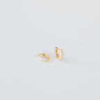 Kira Pave Huggies in small gold feature pavé white stones and are displayed on a plain white surface.